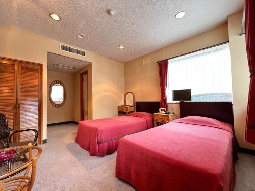 two beds in a hotel room with red covers at リゾートハウス秋桜 in Ōtaki