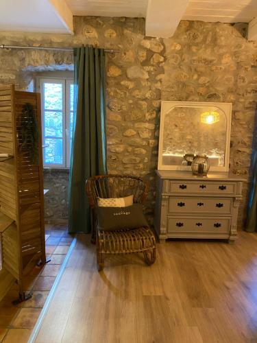 a room with a dresser and a chair with a mirror at Le Bruit de l'eau (Chambre Boudoir) in Labeaume