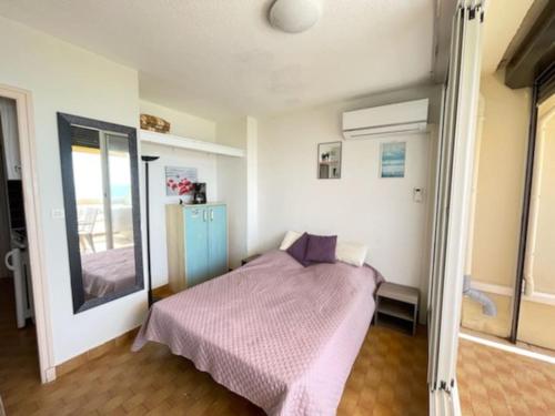 - une chambre avec un lit et une couverture violette dans l'établissement Studio 29, Héliopolis O au village naturiste, au Cap d'Agde