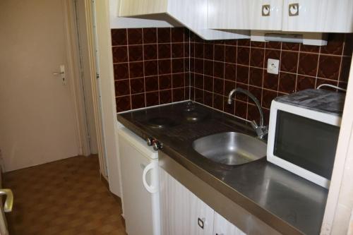 une cuisine avec un évier et un micro-ondes dans l'établissement Studio 29, Héliopolis O au village naturiste, au Cap d'Agde