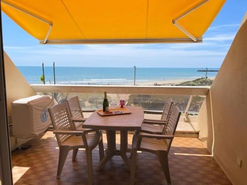 une table et des chaises sur un balcon avec vue sur la plage dans l'établissement Studio 29, Héliopolis O au village naturiste, au Cap d'Agde