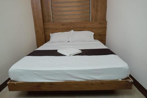 a bed with a wooden headboard and white sheets at Comfort INN in Payyannūr