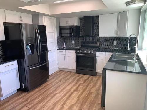 a kitchen with black and white appliances and wooden floors at Rooms at The Blue House in Austin