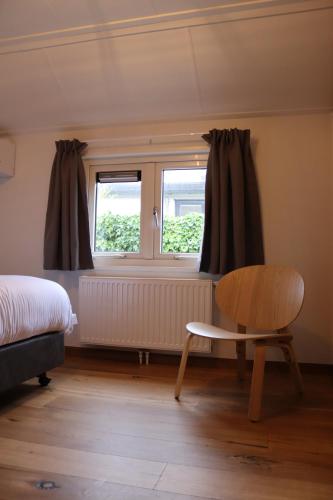 a bedroom with a bed and a window and a chair at Hoeve de Zeeanjelier in Sint Annaland