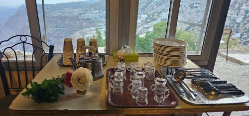 a table with plates and glasses on a table with a view at Dana Village Camp-Wadi Dana Eco camp in Dana