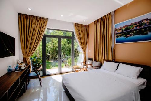 a bedroom with a white bed and a large window at Lancelynk Retreat Hoi An in Hoi An