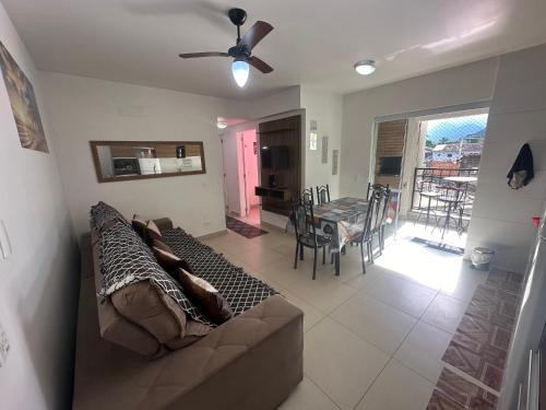 ein Wohnzimmer mit einem Sofa und einem Tisch mit Stühlen in der Unterkunft Lindo Ap - CENTRO- piscina, churrasqueira gourmet, maquina lava e seca e wifi -edifício Jathy in Ubatuba