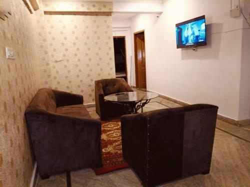 a room with two chairs and a table and a television at The Urban Heaven in Lucknow