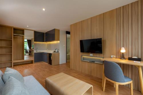 a living room with a couch and a table and a television at Wyndham Garden Naithon Phuket in Nai Thon Beach