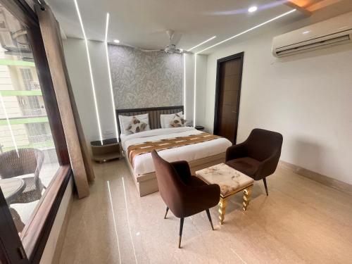 a bedroom with a bed and two chairs and a table at Gazebo Inn & Suites Medanta in Gurgaon