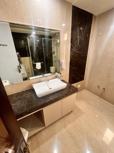 a bathroom with a sink and a large mirror at Gazebo Inn & Suites Medanta in Gurgaon