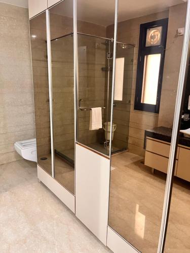 a glass shower in a bathroom with a toilet at Gazebo Inn & Suites Medanta in Gurgaon