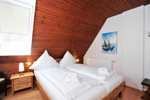 ein Schlafzimmer mit einem weißen Bett und einer Holzwand in der Unterkunft Ferienwohnung-Nr-287 in Böhl