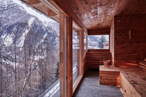 a room with a large window in a wooden house at Goldene Rose Karthaus a member of Small Luxury Hotels of the World in Senales
