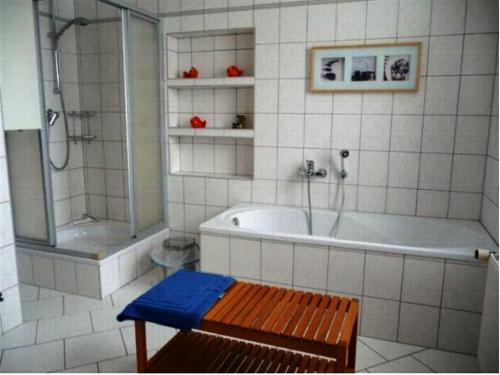 a bathroom with a tub and a shower and a bench at Ferienwohnung Lara in Zinnowitz