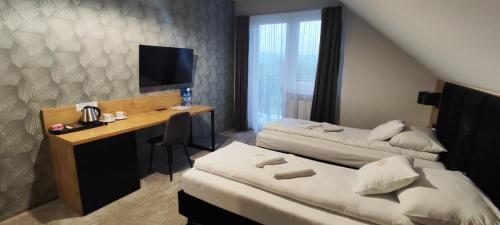 a hotel room with two beds and a desk and a television at Karczma u Jana in Kuczów