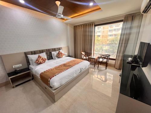 a bedroom with a bed and a table and a window at Gazebo Inn & Suites Medanta in Gurgaon