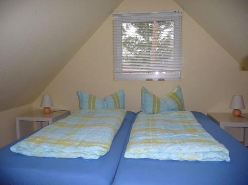 - une chambre avec 2 lits avec des draps bleus et une fenêtre dans l'établissement Ferienhaus Fredy, à Zinnowitz