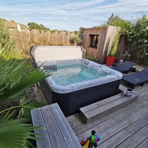 una bañera de hidromasaje en una terraza en un patio trasero en Au Poème du Chêne, Logement indépendant, Intimité, SPA et bien-être en Basse-Goulaine