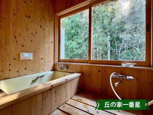 a bath tub in a wooden bathroom with a window at まんのう清流庵 in Manno