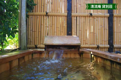 a bench in a pond with a water fountain at まんのう清流庵 in Manno