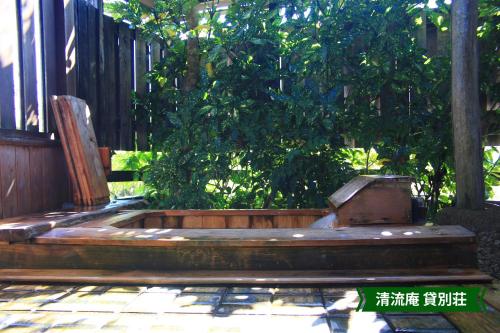 a wooden bench on a porch with a tree at まんのう清流庵 in Manno