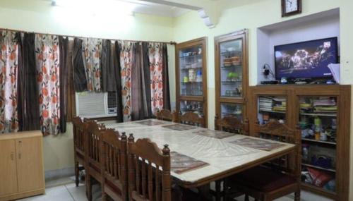 BOBY HOME STAY "BOBY MANSION" Jaipur في جايبور: غرفة طعام مع طاولة وكراسي وتلفزيون