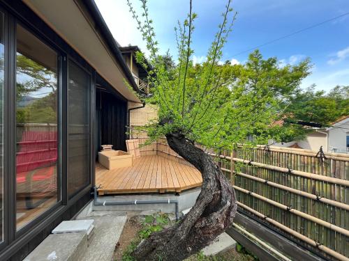 a tree on a deck next to a house at Suite Villa Atami Bettei Soubaian in Atami