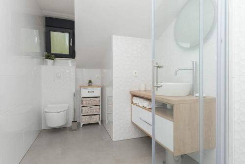 a white bathroom with a sink and a toilet at Sun Paradise Apartment in Podgora