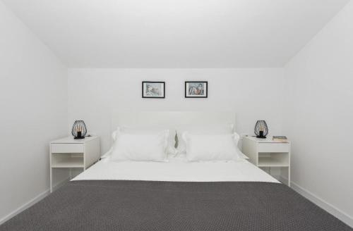 a white bedroom with two white tables and a bed at Sun Paradise Apartment in Podgora