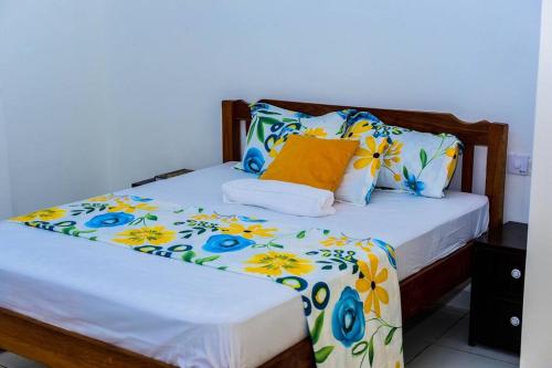 un letto con coperta a fiori e cuscini sopra di Double A Unique Homes a Mombasa