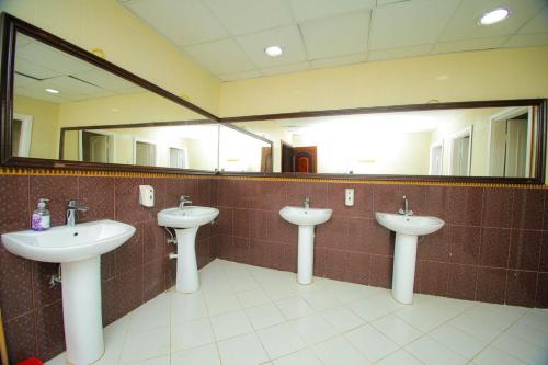 a bathroom with three sinks and two mirrors at فندق ربا الحجاز in Aţ Ţunḑubāwī