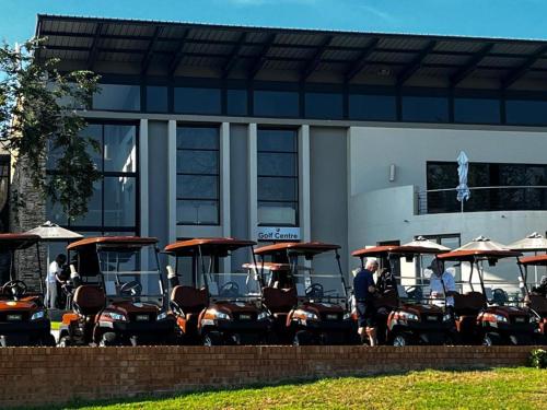 un grupo de carros de golf estacionados frente a un edificio en 82 St Andrews Jackal Creek Golf Estate with Backup power & Golf course views, en Roodepoort