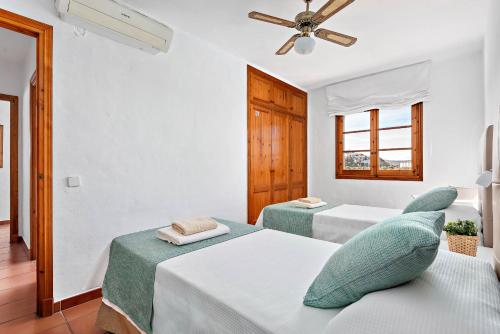 a bedroom with two beds and a ceiling fan at Villas Playas de Fornells in Fornells