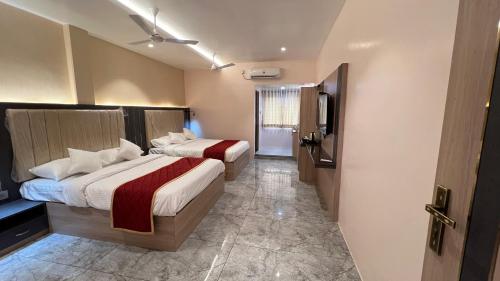 Cette chambre comprend deux lits et une télévision. dans l'établissement GB RESIDENCY, à Ramanathapuram