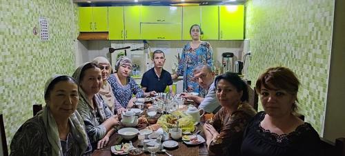 un grupo de personas sentadas alrededor de una mesa en Anisa- Hostel, en Dushanbe