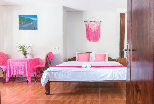 a bedroom with a bed and a table with pink chairs at Nary Garden in Kampot