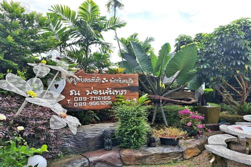 a sign in a garden with flowers and plants at Huen Pak Mon Chantra in Chiang Rai