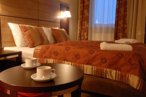 コウォブジェクにあるApartament Delux w Hotelu Diva - Kołobrzegのベッド、テーブル、カップ付
