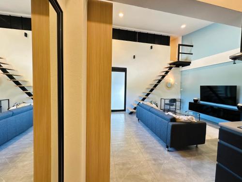 a living room with two blue couches and a staircase at Gloria’s Home in Kamala Beach