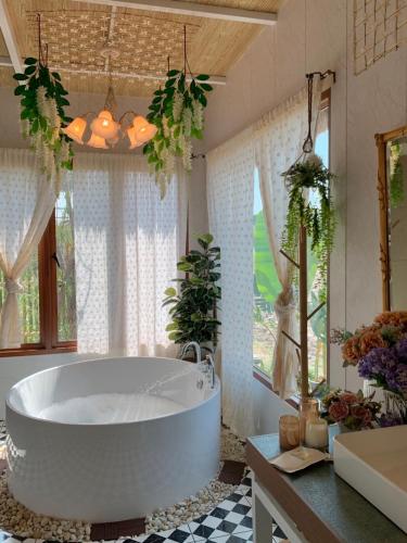 a large white tub in a bathroom with windows at กลิ่นไอทุ่งโฮมสเตย์ in Ban Thum