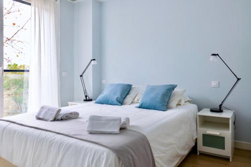 a bedroom with a white bed with blue pillows at Apart jardines San Vicente in Madrid