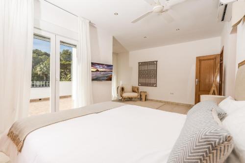 ein weißes Schlafzimmer mit einem großen Bett und einem Fenster in der Unterkunft Casa Oleander in Balcon del Mar