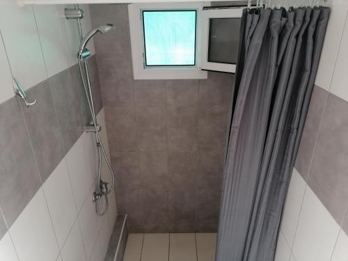 a bathroom with a shower curtain and a window at Porto Almira Studio in Nikiti