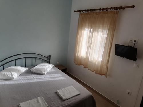 a bedroom with a bed with two pillows and a television at Porto Almira Studio in Nikiti