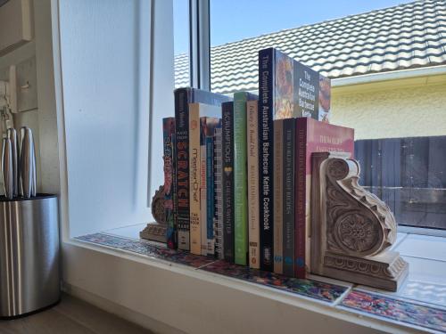 a row of books sitting on a window sill at Beautiful haven near airport! in Christchurch