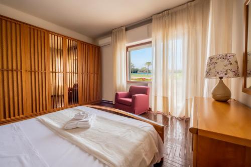 a bedroom with a bed and a chair and a window at Vintage al Mare_ fronte spiaggia in Porto SantʼElpidio