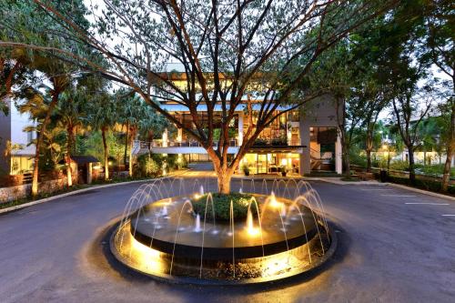 a fountain with a tree in the middle of a street at The Park Nine Hotel Srinakarin in Bangkok