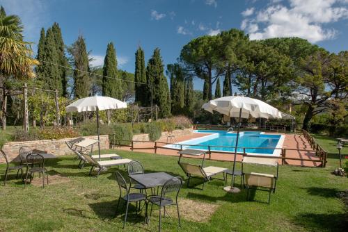 um quintal com cadeiras e guarda-sóis e uma piscina em Tenuta di Caiolo em Panicale