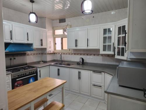 a kitchen with white cabinets and a wooden table at شقة عائلية فخمة in Al Madinah